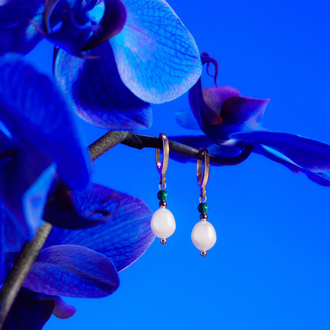 Orecchini di perle su sfondo blu con fiore